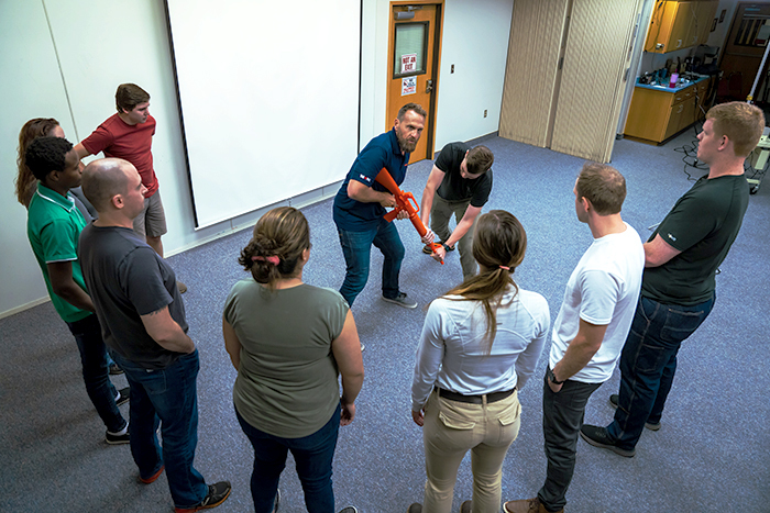 A man demonstrates how to disarm a shooter using an orange prop gun